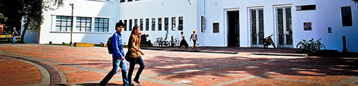 Un chico y una chica caminando frente a una facultad en la universidad nacional